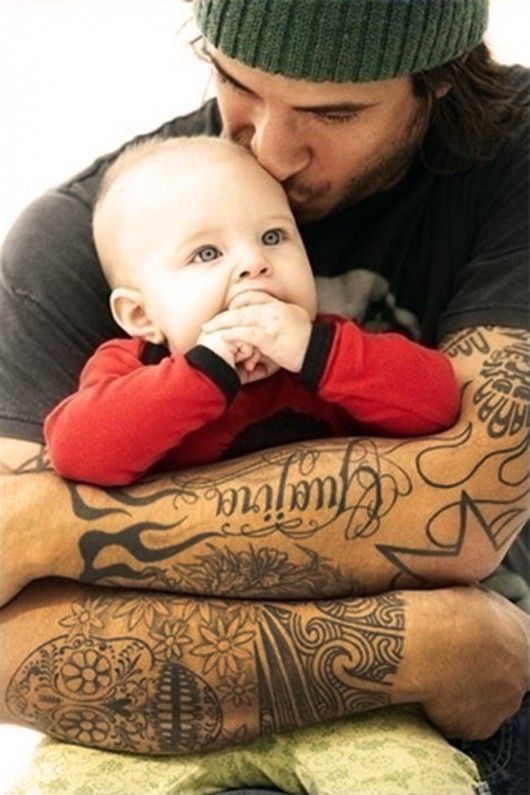 Père tatoué câlin et bisou bébé